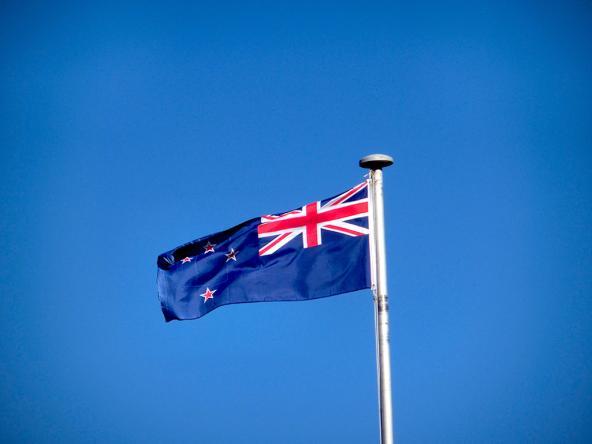Die Flagge Neuseelands vor strahlend blauem Himmel