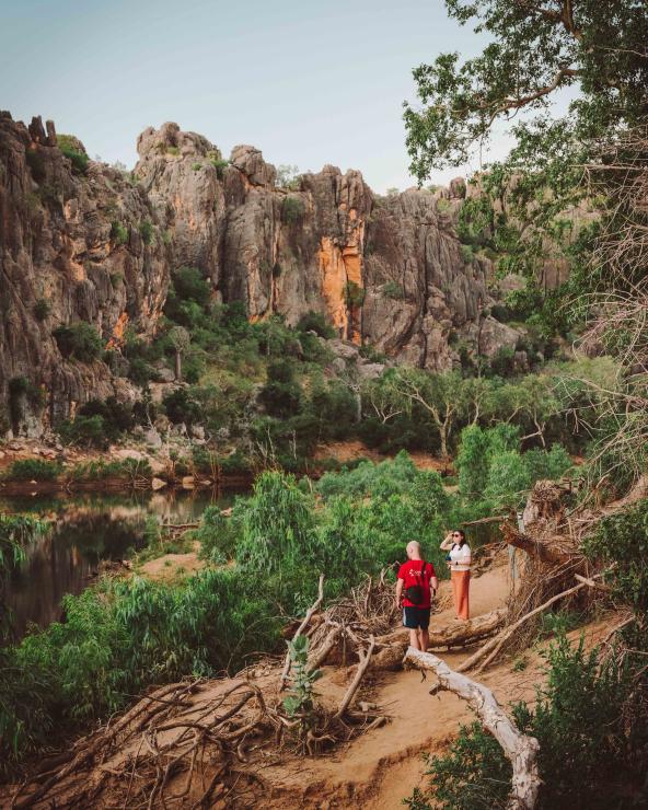 Zwei Personen stehen auf einem Pfad mit Blick auf die steilen Felswände und den Fluss der Windjana Gorge