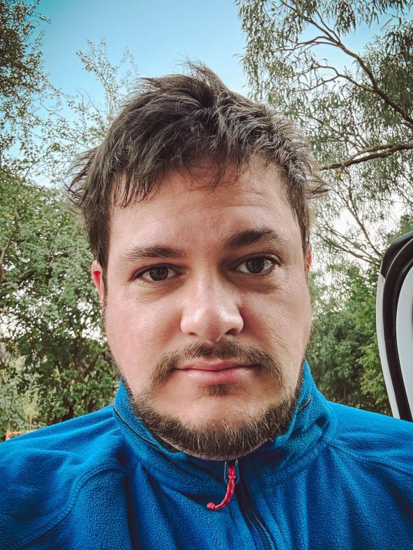 Person mit zerzausten Haaren und blauer Fleecejacke nach einer kalten Nacht im Zelt