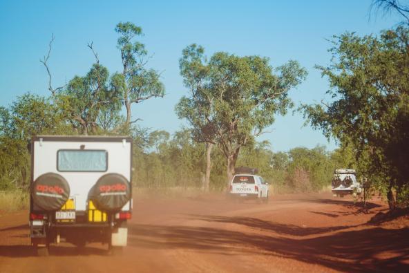 Drei Allradfahrzeuge fahren auf einer staubigen roten Piste durch das australische Outback
