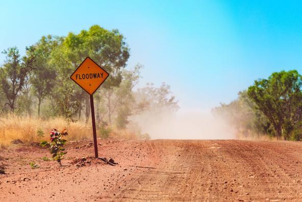 Floodway-Warnschild an roter Schotterstraße im australischen Outback