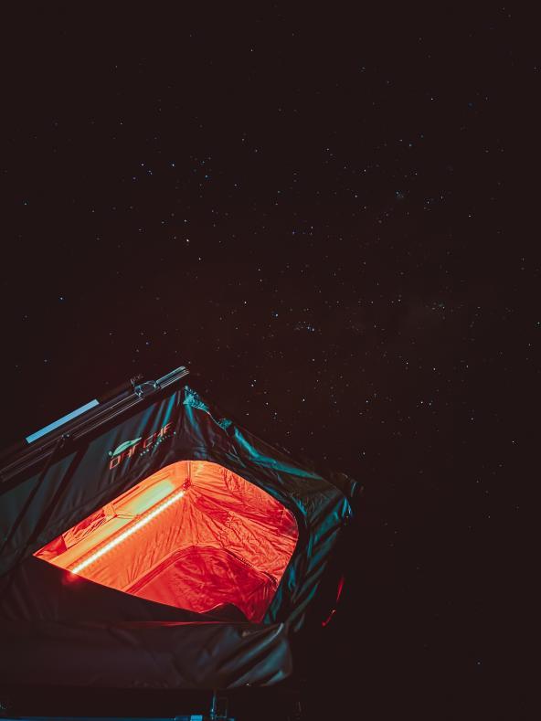 Beleuchtetes Dachzelt unter sternenklarem Nachthimmel im australischen Outback