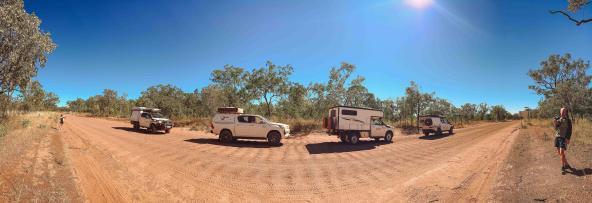 Mehrere Geländefahrzeuge stehen auf einer roten Schotterstraße im australischen Outback, um die Länge eines Road Trains nachzustellen