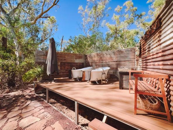 Zwei freistehende Badewannen auf einer Holzterrasse zwischen Wellblechwänden unter freiem Himmel bei der Ellenbrae Homestead