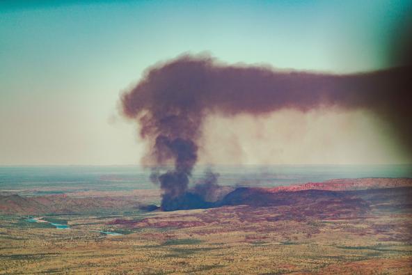 Dichter Rauch steigt als hohe schwarze Säule über der Landschaft der Kimberleys auf.
