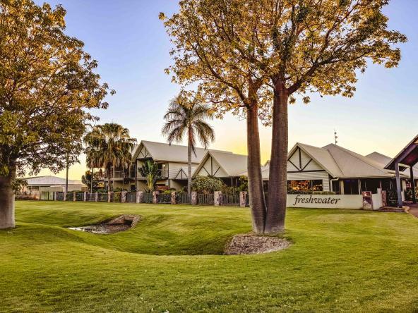 Außenansicht der Freshwater Apartments in Kununurra mit gepflegtem Rasen und tropischen Bäumen.