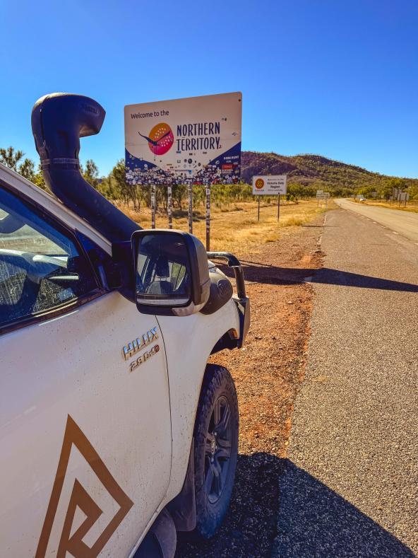 Geländewagen vor dem „Welcome to the Northern Territory“-Schild an der Grenze zwischen Western Australia und dem Northern Territory.