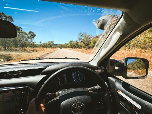 Blick aus dem Fahrzeug auf eine lange, gerade Straße im Northern Territory, aufgenommen vom Fahrersitz.