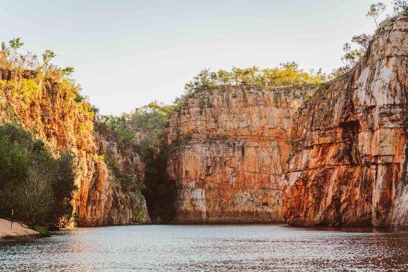 Sandsteinwände der Katherine Gorge bei tiefstehender Sonne, mit Fluss im Vordergrund.