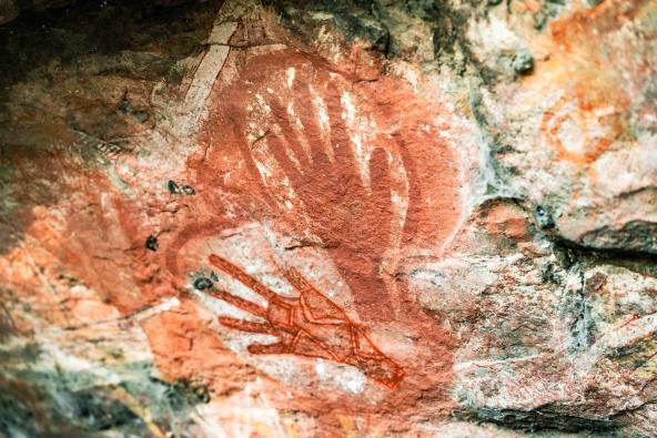 Felsmalereien zeigen zwei Handabdrücke und eine stilisierte rote Figur auf einer Felswand.